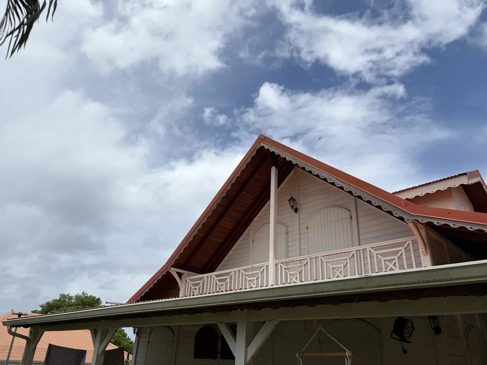Façade de la Villa Bas-Pellée, maison créole blanche au toit orange avec balcon en bois ouvragé, Martinique